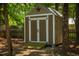 A wooden shed with double doors and a star adornment sits nestled amongst the trees at 102 Bluegrass Dr, Oxford, NC 27565