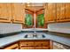 Cozy kitchen featuring corner windows, stainless steel sink, granite countertops, and wood cabinets at 1030 W Sterlington Pl, Apex, NC 27502