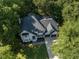 Overhead view of gray brick home with mature trees, green lawn and long driveway at 104 Warley Cir, Cary, NC 27513