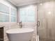 A luxurious bathroom features a soaking tub under a window with plantation shutters and a walk-in shower at 104 Warley Cir, Cary, NC 27513