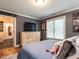 A bedroom with grey walls features a dresser with a TV, and a glimpse of an ensuite bathroom at 104 Warley Cir, Cary, NC 27513