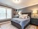 A bedroom with grey walls features two windows with blinds, a neutral bed, and hardwood floors at 104 Warley Cir, Cary, NC 27513