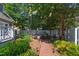 Landscaped backyard with brick pathway, mature trees, dining set and white picket fence at 107 Quarter Path, Cary, NC 27518