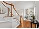 Elegant foyer featuring hardwood floors, stairs with wood railing, and built-in shelving with stylish decor at 107 Quarter Path, Cary, NC 27518