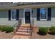 Charming home exterior with brick steps and a black front door with a decorative wreath, framed by black shutters at 107 Quarter Path, Cary, NC 27518