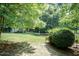 View of the lush backyard with mature trees and plantings surrounding a small outbuilding at 109 Fox Trap Ct, Garner, NC 27529