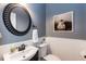 Charming powder room featuring round decorative mirror, artwork, and stylish fixtures at 109 Fox Trap Ct, Garner, NC 27529