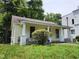 Charming yellow home featuring a covered porch, cozy front yard, and lush surrounding greenery at 1106 Fargo St, Durham, NC 27707