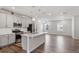 Modern kitchen open to living area, featuring stainless steel appliances, an island, and hardwood floors at 1114 Crossvine Trl, Durham, NC 27703