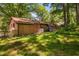 A secluded home backyard with a brick facade, lawn, and some trees at 1120 E Oak Dr, Durham, NC 27712