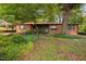 Charming brick home featuring a vibrant blue front door and mature trees in a spacious yard at 1120 E Oak Dr, Durham, NC 27712