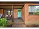 Welcoming brick front porch featuring a quaint seating area and a pop of color with a turquoise door at 1120 E Oak Dr, Durham, NC 27712