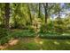 Charming outbuilding nestled amongst trees with landscaping offers a private retreat or storage at 1120 E Oak Dr, Durham, NC 27712