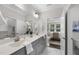 Bright bathroom featuring double sink vanity, marble floors, and an open doorway to the main bedroom at 1125 Surveyor Dr, Durham, NC 27703
