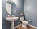 Well-lit half bathroom featuring a pedestal sink, toilet and a decorative mirror at 125 Alumroot Rd, Holly Springs, NC 27540