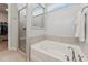 Bright bathroom featuring a large tub, walk-in shower, tile accents, and plenty of natural light at 125 Alumroot Rd, Holly Springs, NC 27540