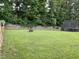 Spacious backyard with lush green grass, wooden fence, and fire pit at 1276 Dalgarven Dr, Apex, NC 27502