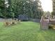 Expansive backyard with lush green grass, wooden fence, fire pit, deck and trampoline at 1276 Dalgarven Dr, Apex, NC 27502