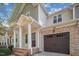 Charming townhouse featuring a stone facade, brown garage door, and covered front porch with brick steps at 145 Mariah Towns Way, Garner, NC 27529