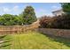 Backyard showcasing a well-maintained lawn and a charming stone retaining wall with mature trees at 200 Woodvale Way, Fuquay Varina, NC 27526
