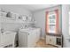 Well-lit laundry room with washer, dryer, utility sink, shelving, and storage cabinet at 200 Woodvale Way, Fuquay Varina, NC 27526
