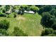 Aerial view of a large field with a home and outbuildings. Lush greenery surrounds the property at 2081 Stone Street Ext, Mebane, NC 27302