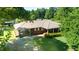 Aerial view of a brick home with metal roof, covered parking, and mature trees at 2081 Stone Street Ext, Mebane, NC 27302