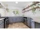 Updated kitchen with gray cabinets, stainless steel appliances, floating shelves, white tile backsplash, and large window at 220 Oxfordshire Dr, Fuquay Varina, NC 27526