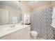 Well-lit bathroom featuring a vanity, sink, toilet, and a shower with a patterned curtain at 302 Caraway Ln, Cary, NC 27519
