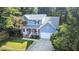 Two-story home featuring a classic front porch, attached garage, and a sloped driveway amidst lush greenery at 302 Caraway Ln, Cary, NC 27519