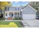 Beautiful two-story home with a charming front porch, brick stairs, and a two-car garage, surrounded by green lawn at 302 Caraway Ln, Cary, NC 27519