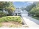 Inviting two-story home featuring a classic front porch, attached garage, and a sloped driveway amidst lush greenery at 302 Caraway Ln, Cary, NC 27519