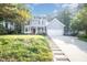 Inviting two-story home featuring a classic front porch, attached garage, and a sloped driveway amidst lush greenery at 302 Caraway Ln, Cary, NC 27519