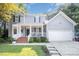 Beautiful two-story home with a charming front porch, brick stairs, and a two-car garage, surrounded by green lawn at 302 Caraway Ln, Cary, NC 27519