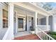 Welcoming front porch with a dark front door, white pillars and cozy seating at 302 Caraway Ln, Cary, NC 27519
