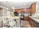 Well-lit kitchen featuring an island with bar stool seating, granite countertops, and wood-look flooring at 3037 Willow Ranch Dr, Fuquay Varina, NC 27526