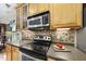 Close-up of stove and counter featuring tile backsplash, stainless oven, and wood cabinets at 3207 Imperial Oaks Dr, Raleigh, NC 27614