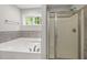 Bathroom featuring a luxurious soaking tub and glass-enclosed shower, complemented by a window providing natural light at 3401 Grosbeak Way, Raleigh, NC 27616