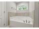 Bright bathroom featuring a soaking tub beneath a window with natural light complemented by tile backsplash at 3401 Grosbeak Way, Raleigh, NC 27616