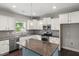 Well-lit kitchen featuring white cabinets, stainless steel appliances, granite countertops, and a kitchen island at 3401 Grosbeak Way, Raleigh, NC 27616