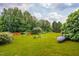 Expansive backyard with lush greenery, mature trees, and landscaped garden beds on a sunny day at 3619 Nc-57, Hillsborough, NC 27278
