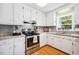 Galley kitchen featuring white cabinets, stainless steel appliances, granite countertops, and backsplash at 3619 Nc-57, Hillsborough, NC 27278
