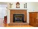 Close up of a fireplace with red brick and a wooden cabinet against a white wall at 3619 Nc-57, Hillsborough, NC 27278