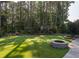 Large backyard with manicured lawn, stone fire pit, and wooded backdrop for a peaceful outdoor living space at 3624 Regent Pines Dr, New Hill, NC 27562