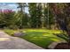Beautiful backyard featuring a well-maintained lawn, a stone fire pit, and surrounding trees and landscaping at 3624 Regent Pines Dr, New Hill, NC 27562