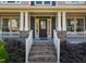 Elegant front porch with a classic door, decorative columns, brick accents, and manicured landscaping at 3624 Regent Pines Dr, New Hill, NC 27562