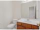Neutral half bath with white toilet, wood vanity and large mirror at 3812 Covina Dr, Raleigh, NC 27613
