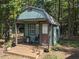 Cozy green shed with a porch, single door, and window, surrounded by lush greenery at 4008 Old Nc 86, Hillsborough, NC 27278