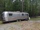 Exterior view of vintage Airstream trailer with aluminum siding in wooded backyard at 4008 Old Nc 86, Hillsborough, NC 27278