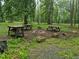 Wooded backyard fire pit area with picnic tables surrounded by natural landscaping and trees at 4008 Old Nc 86, Hillsborough, NC 27278
